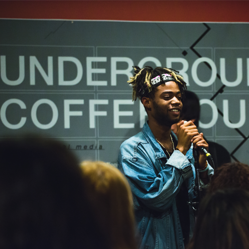 performer holding microphone inside underground coffehouse